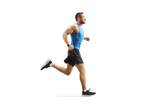 Full length profile shot of a young man jogging isolated on white background