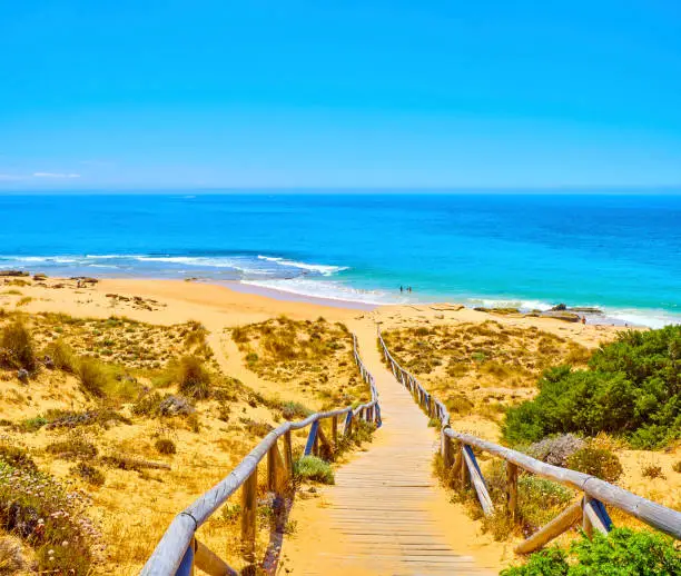 Wooden boardwalk going to Faro de Trafalgar Beach, a broad beach of The Cabo de Trafalgar Cape Natural Park. Barbate, Los Caños de Meca, Cadiz. Andalusia, Spain.