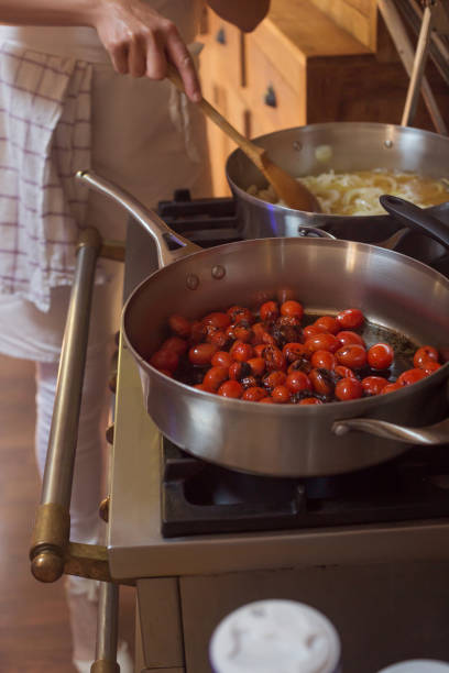 istock Pan with caramelised tomatoes cherry process of cooking and adding ingredients hands 1167096928