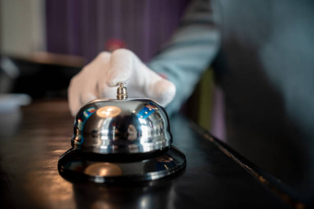 ホテルのチェックインカウンターでベルを鳴らす認識できないベルホップのクローズアップ - hotel occupation concierge bell service ストックフォトと画像
