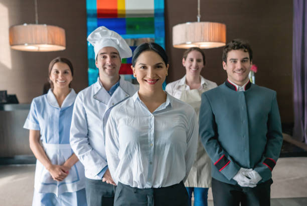 Portrait of cheerful luxury hotel staff smiling at camera and female supervisor standing at foreground Portrait of cheerful luxury hotel staff smiling at camera and female supervisor standing at foreground - Hotel occupation concepts bellhop photos stock pictures, royalty-free photos & images