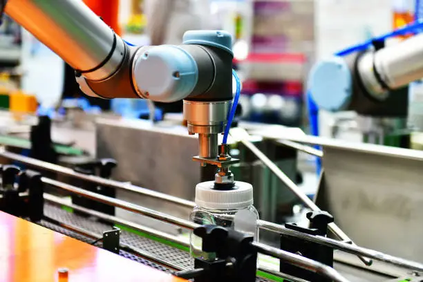 Robot arm arranged glass water bottle on Automatic industrial machinery equipment in production line factory