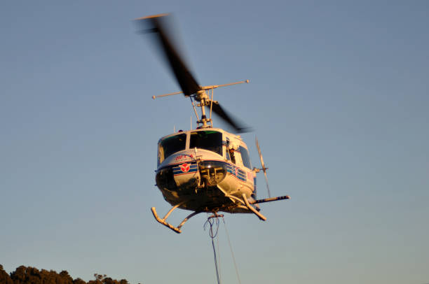 helicopter taking off Greymouth, New Zealand, circa 2009: Iroquois helicopter takes off with a load of 1080 pellets in a monsoon bucket. The 1080 pellets are a controversial method of controlling possums in New Zealand's native bush. possum nz stock pictures, royalty-free photos & images
