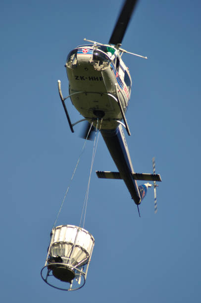 another 1080 drop Greymouth, New Zealand, circa 2009: Iroquois helicopter takes off with a load of 1080 pellets in a monsoon bucket. The 1080 pellets are a controversial method of controlling possums in New Zealand's native bush. possum nz stock pictures, royalty-free photos & images