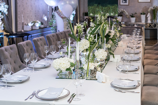 A table set up for the bride and groom at a wedding celebration, with placards, flowers and crockery