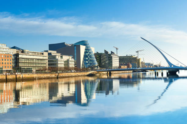 Modern buildings and offices on Liffey river in Dublin Modern buildings and offices on Liffey river in Dublin on a bright sunny day, bridge on the right is a famous Harp bridge. republic of ireland stock pictures, royalty-free photos & images