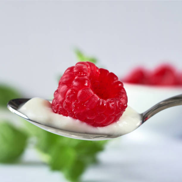 istock Spoon filled with yoghurt and a raspberry on top on light 1167142793