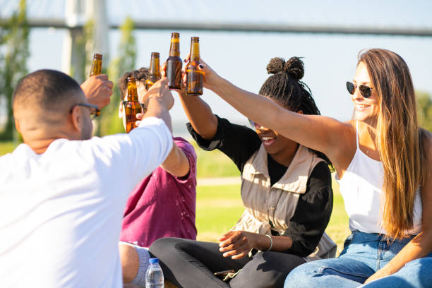 istock Relaxed young people clinking beer bottles in park. 1167142963
