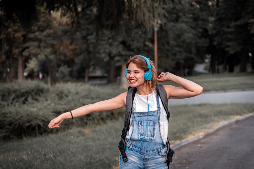 Beautiful young girl using smartphone and headphones,she is playing music using a smartphone and wearing Blue headphones.listen to music, park, outdoor