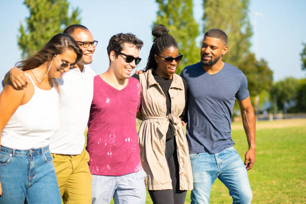 istock Group of smiling friends hugging while walking on meadow. 1167145403