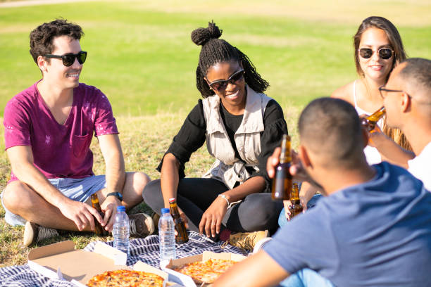 istock Smiling friends drinking beer while sitting on meadow. 1167147489