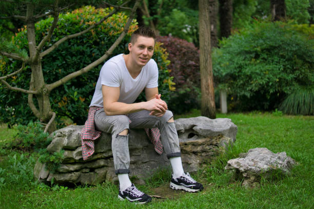 istock Young man sitting on a rock in park 1167148893