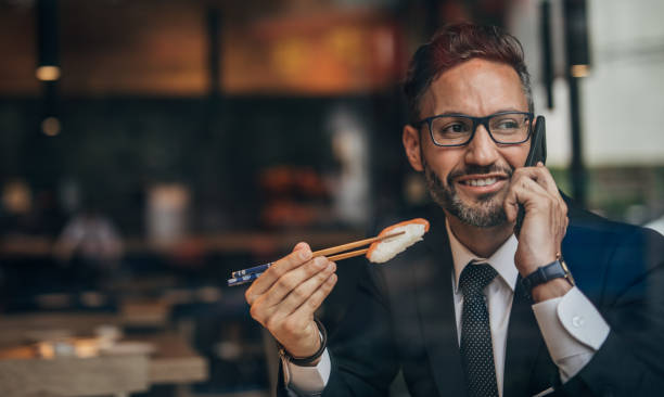istock Businessman eating sushi and talking on mobile 1167156562