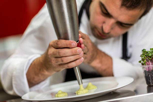 istock Restaurant chef using a cream dispenser to put small cream puddles on a plate 1167167387