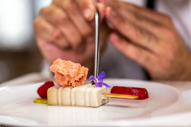 Putting a blue jasmine flower as a decoration on a molecular cuisine dish made to look like an ice cream stock photo