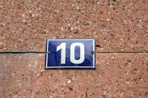 enameled house number on a wall of natural stone