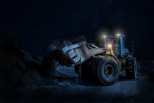 Mining wheel loader Scooping Gravel on a night time construction project with its lights on