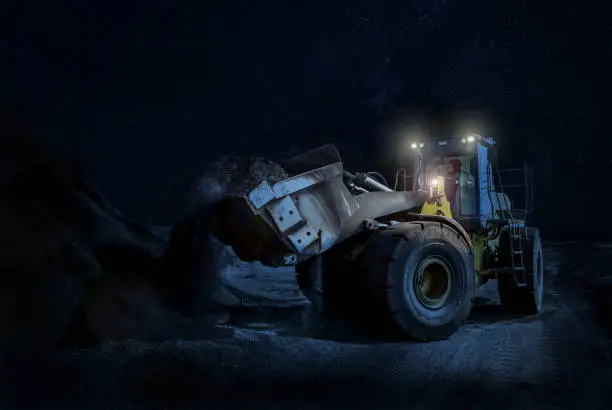 Mining wheel loader Scooping Gravel on a night time construction project with its lights on