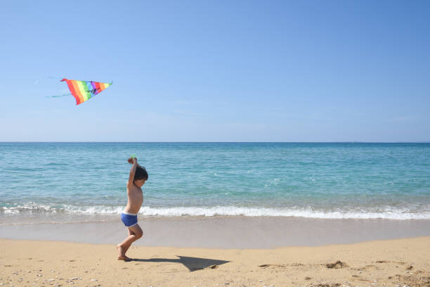 istock Little boy playing with kite on tropical beach 1167173993