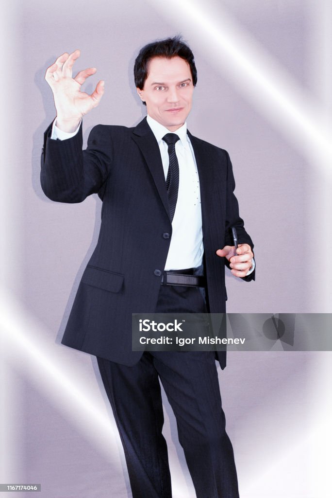On the way to success. Business life. Purposeful attractive businessman, holding his smartphone, smiles and shows ok sign. Business life in the office. Adult Stock Photo