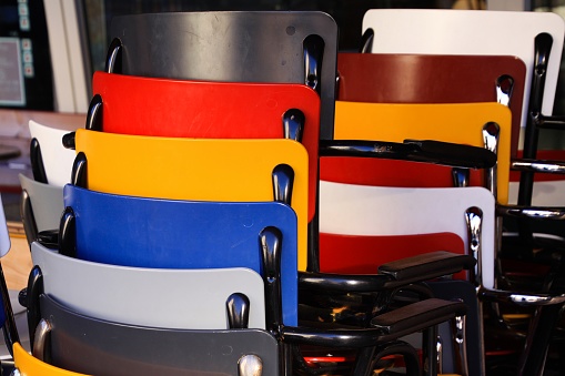 Multicolored chairs piled up in front of a restaurant