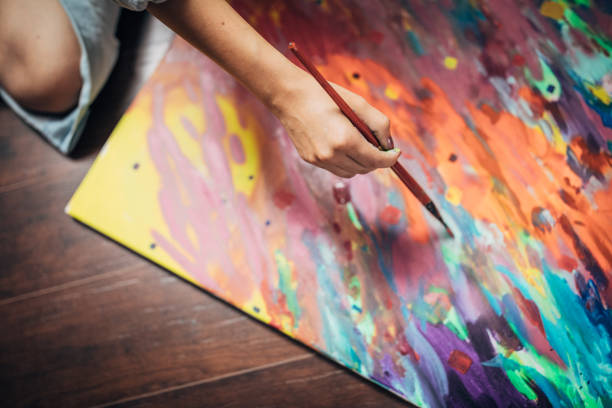 One woman, lady artist, painting on the floor in studio, close up.