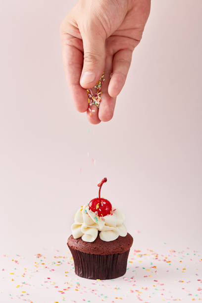 istock Cupcake decoration. Hand decorating cupcake with some sprinkles on cherry on top. 1167176917