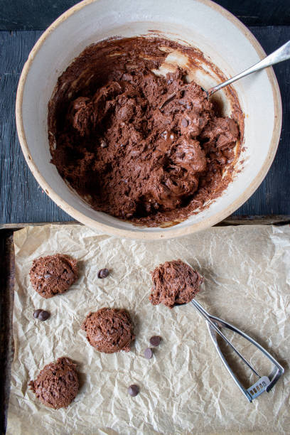 istock scooping out chocolate chip cookie dough batter onto wax paper cookie sheet 1167180174