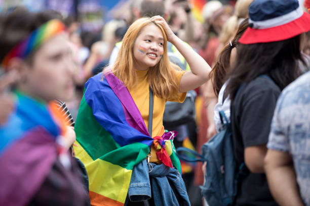 woman wearing a rainbow scarf over her shoulder at a gay pride parade on a city street - urban scene regent street city of westminster inner london imagens e fotografias de stock