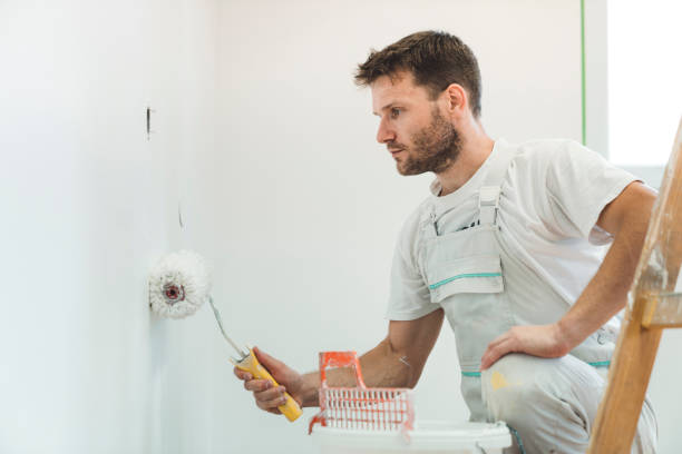 istock Painter looking at the paint roller, painting the wall 1167186897