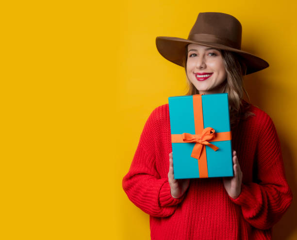 istock Young smiling woman in red sweater with gift box 1167187303