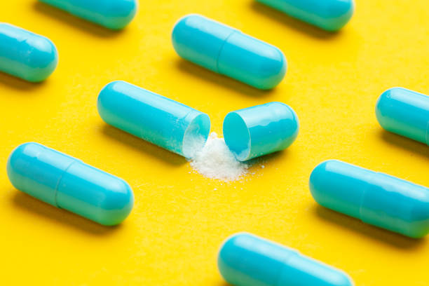 istock Blue tablets in capsules. One capsule is open. Yellow background. 1167189099