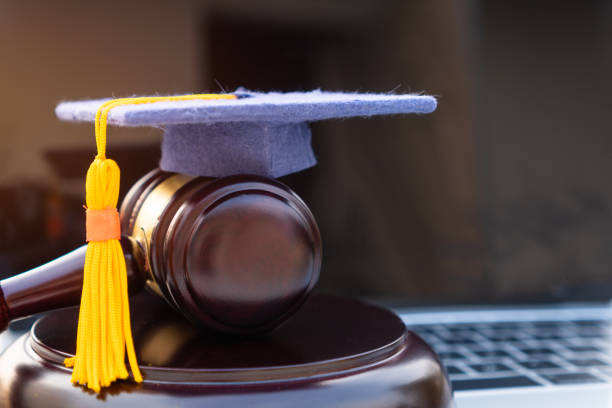 istock Graduation diploma hat / Judge gavel on computer notebook. Concept of graduate online study international abroad about jurisprudence laws certificate in university distance education for learning. 1167189682