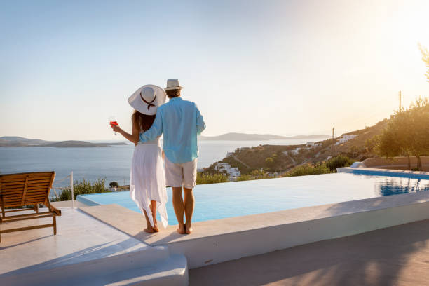 Couple enjoys the summer sunset by the pool Happy couple on vacation time enjoys the summer sunset by the pool with an aperitif drink vista posterior stock pictures, royalty-free photos & images