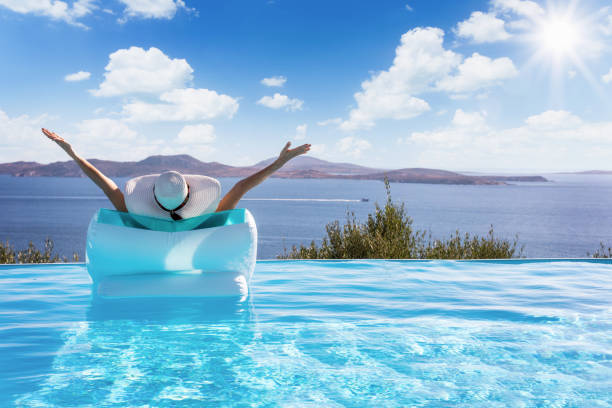 le femme flotte sur une piscine avec vue à la mer méditerranée - sea swimming greece women photos et images de collection