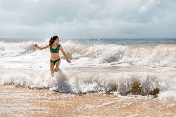 istock Young beautiful girl running from crashing wave ate the beach 1167201737