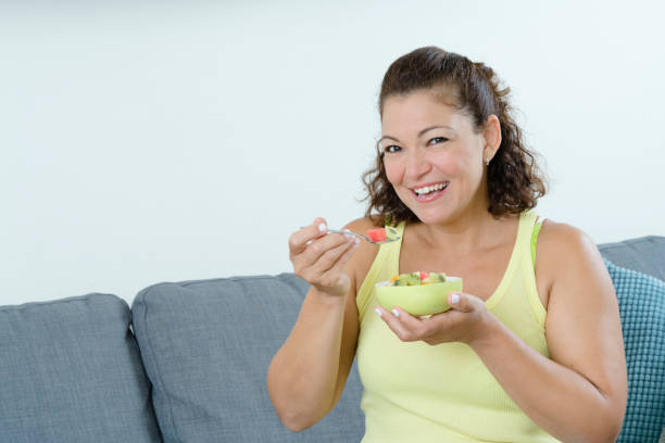 istock Woman sitting on couch eating yogurt 1167208813