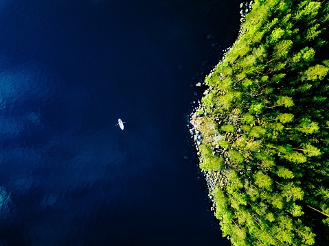 Vista aérea del lago azul con un barco de pesca y bosques verdes con rocas en Finlandia. photo