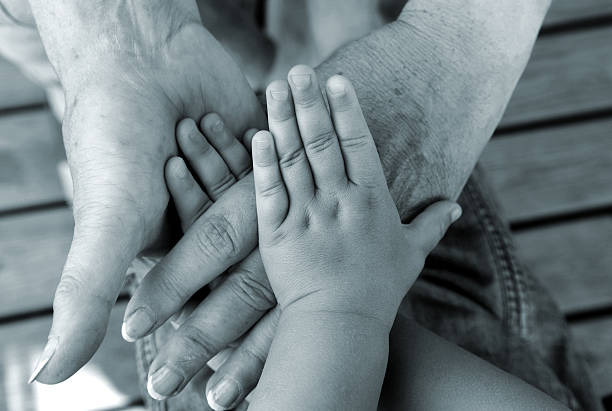 Child hand holding old woman's hand. Grandmother and grandson hold hands. Diverse hands, family, help and aging process concepts. Horizontal close-up details.