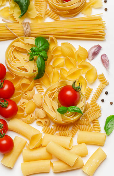 istock Various uncooked pasta on white background. Top view. Raw pasta with ingredients for cooking. Food concept 1167213552