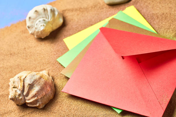 istock Seashells, colorful paper envelopes and scattered dry sand on blue scratched concrete 1167219986