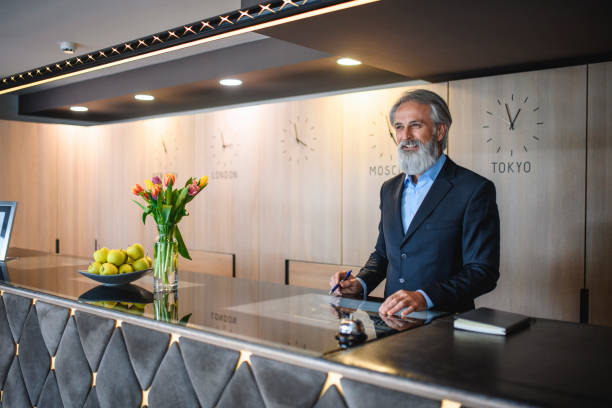 istock Cheerful Bearded Senior Hotel Receptionist at Front Desk 1167221165