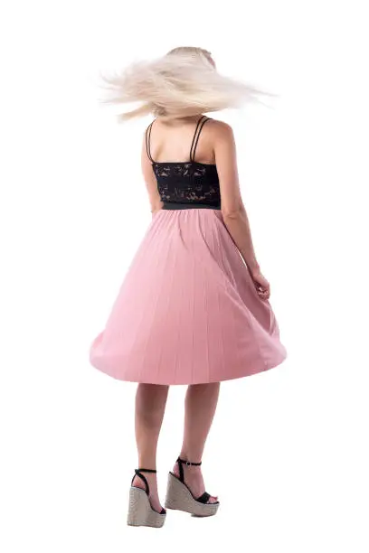 Back view of blonde young woman in summer skirt spinning and dancing with flying hair. Full body isolated on white background.