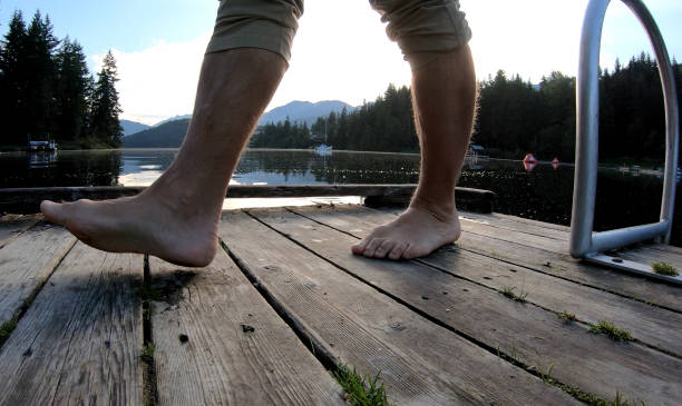 istock Low angle view of man walking barefoot across dock at sunrise 1167228798