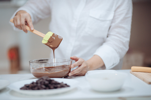 an asian chinese female desert chef preparing chocolate truffles at home mixing and scrapping chocolate