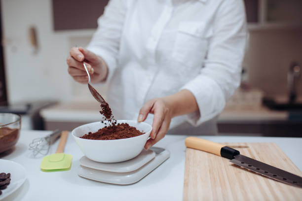 eine asiatische chinesische weibliche wüstenköchin bereitet schokoladentrüffel zu hause mit dem lernen von digitalen tablet e lernen rezept wiegen zutat - küchenwaage stock-fotos und bilder