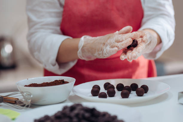 an asian chinese female chef preparing chocolate truffles at home in domestic kitchen an asian chinese female chef preparing chocolate truffles at home in domestic kitchen chocolate truffle making stock pictures, royalty-free photos & images