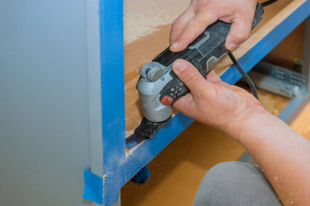 キッチン家具のハンディマンカット穴のための振動多機能切断ツールを使用して請負業者 - home improvement carpentry construction work tool ストックフォトと画像