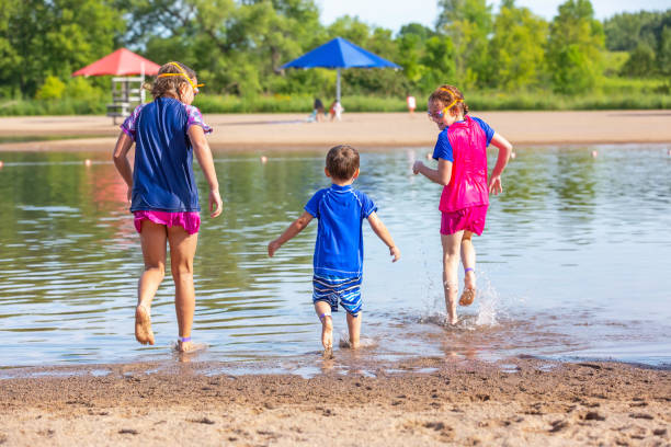 istock Two Girls & Boy Running Into Water At Beach 1167236615