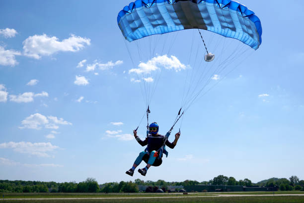 Man with a blue little canopy of a parachute is flies, close-up. High-speed landing of a Skydiver with parachuter against the background of clouds.  USA, Michigan